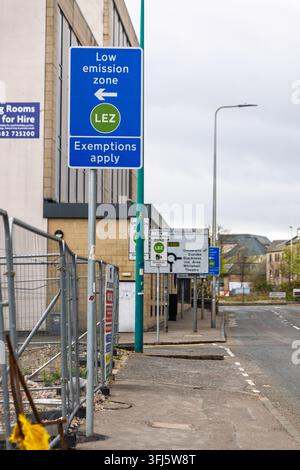 Blue LEZ directional sign mounted on pole beside construction hoarding on urban street in Dundee, with further signage visible indicating University o Stock Photo