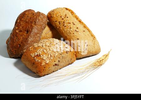 Various types of fresh baked whole grain bread rolls and wheat spikelets presenting healthy breakfast and bakery concepts Stock Photo