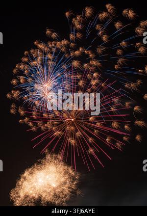 Blue, red and golden fireworks form vivid bursts and sparkling trails Stock Photo
