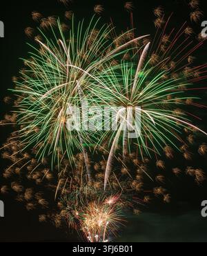 Spectacular green and golden fireworks create sweeping arcs and bright trails across the dark night sky. Stock Photo