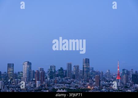 A stunning panoramic view providing ample copy space, featuring an illuminated city skyline and prominent architectural landmarks under a deep blue tw Stock Photo