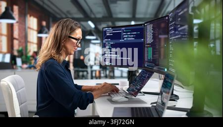 Software Developer Woman Coding Secure Programs On Laptop In Modern Workspace. Stock Photo