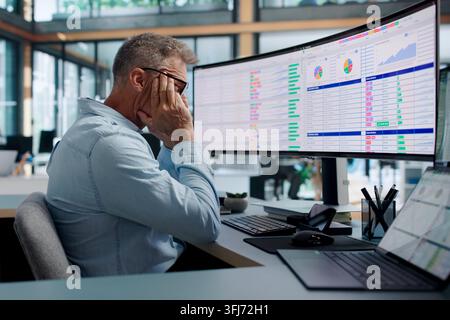 Chartered Accountant Tiredly Reviewing Complex Billing Codes On Computer Display. Stock Photo