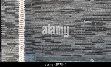 Facade cladding using long, linear clinker bricks. Decorative masonry featuring a mélange gradient of gray and anthracite tones. Stock Photo