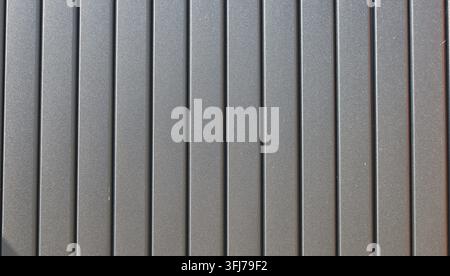Graphite-colored metal euro-picket fencing. The planks have a matte powder coating with a fine, rough texture. Metal vertical euro picket fence Stock Photo