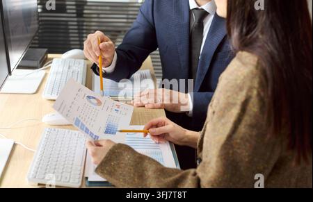 Colleagues analyzing financial charts together at desk during office planning Stock Photo