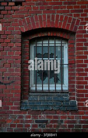 Broken window with iron bars in an old red brick wall Stock Photo
