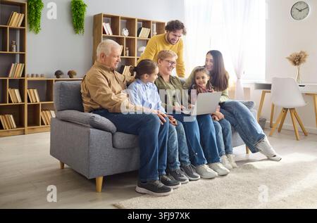Happy multigenerational family using laptop at home, bonding and learning online Stock Photo