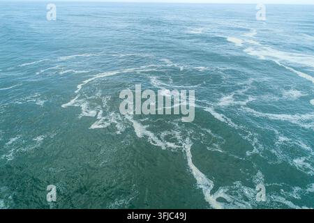 High angle shot of open ocean with white foam lines stretching to the horizon Stock Photo