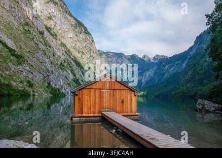 Symmetrical view of a wooden boathouse reflected in the still waters of Obersee lake in the Berchtesgaden Alps, Bavaria, Germany. Stock Photo