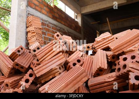 A red clay brick pile inside unfinished construction building with unfinished wall and concrete frame Stock Photo