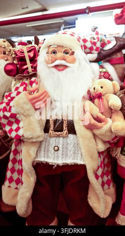 Santa claus figurine stands holding a teddy bear and gift box, celebrating christmas holiday spirit Stock Photo