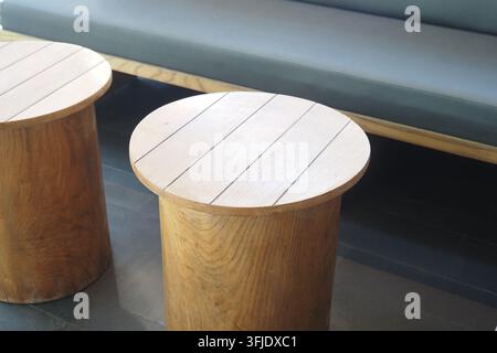 Two wooden stools in a modern setting with a couch in the background Stock Photo