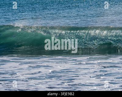 Ocean wave breaking with foamy white water and blue and green tones Stock Photo