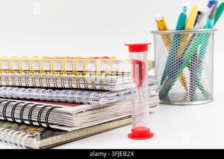 Red Hourglass Beside Stack of School Notebooks and Colorful Stationery Stock Photo
