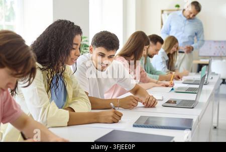 Diverse university students studying in classroom during lecture with teacher Stock Photo