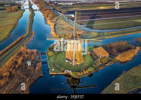 Historic Rietveldse windmill demonstrating traditional Dutch engineering, efficiently pumping water from canals through the interconnected polder system in the South Holland countryside Stock Photo