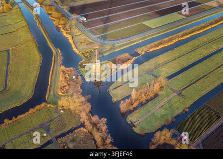 Rietveldse windmill is efficiently managing water levels in Hazerswoude-Dorp, Netherlands, surrounded by intricate canals and agricultural fields creating a vibrant aerial view of the Dutch polder Stock Photo
