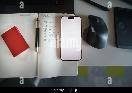 notes tech development, featuring a modern workspace with a smartphone, technical sketches in a notebook, and an ergonomic computer mouse. This techno Stock Photo