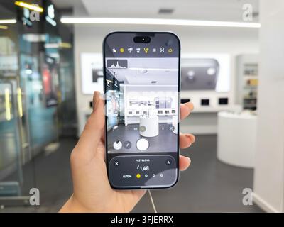 Poznan, Poland - September 19, 2026: Apple iPhone 18 Pro held by a person within a retail electronics shop, using the manual camera interface to adjus Stock Photo
