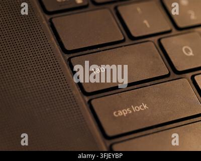 Macro close-up shot focusing on the tab and caps lock keys of a modern black laptop keyboard under warm lighting Stock Photo