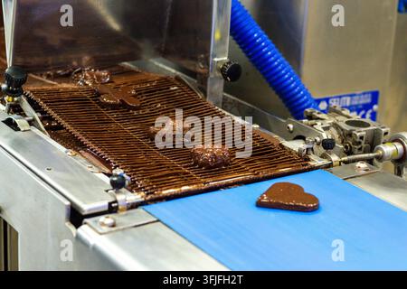 Marzipan candies on blue conveyor belt at factory. Sweets production process Stock Photo