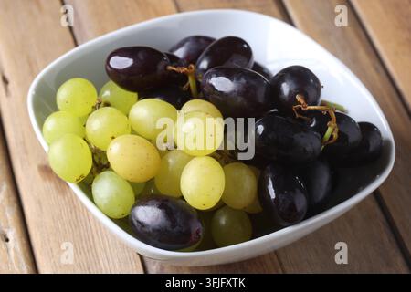 Fresh Green and Red Grapes Arranged in a White Bowl on Wooden Table Stock Photo