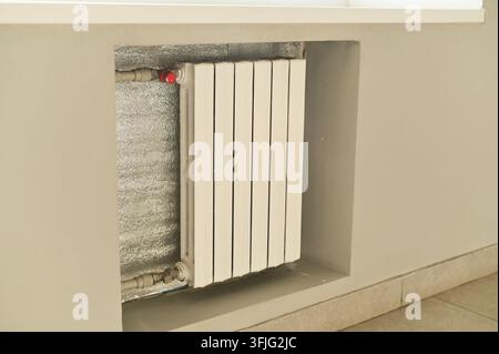 Indoor wall radiator with white vertical panels placed beneath window, heating system in clean interior space, radiator as functional element, modern Stock Photo