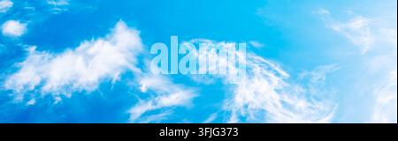 White fluffy clouds float in a bright blue sky. Natural weather, clear atmosphere, outdoor background. Stock Photo