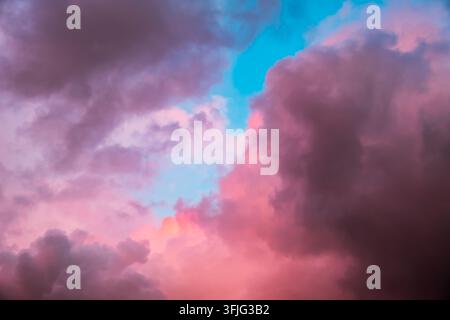 Pink and purple cumulus clouds float in a blue evening sky. Sunset colors, dramatic atmosphere, natural background. High quality photo Stock Photo