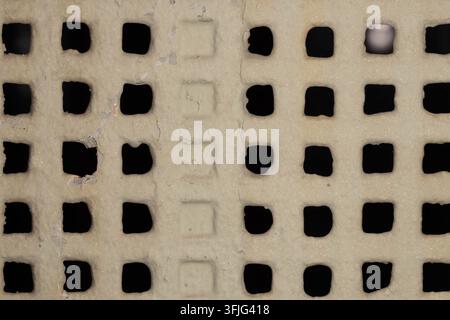 Weathered ventilation grille with geometric square openings. Historic architecture detail suitable for texture and design use. Stock Photo