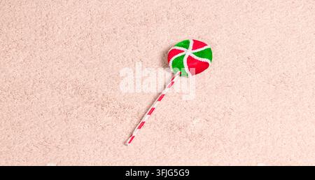 decorative toy candy prop featuring a striped stick and vibrant holiday colors placed on a neutral fabric surface for seasonal winter themes Stock Photo