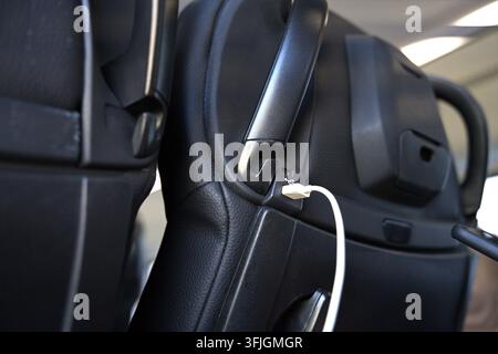 A USB port in the car seat backrest, to which a white charging cable is connected. High quality photo Stock Photo