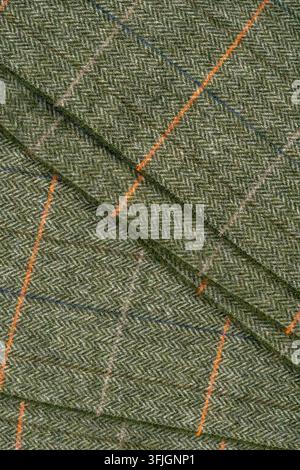 Detailed close-up of textured gray-green woven fabric featuring diagonal folds and bright orange and subtle blue accent threads. Stock Photo