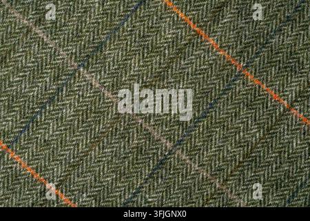 Macro view of coarse green woven fabric with visible gray fibers and irregular orange and blue threads. The detailed textile surface creates a natural Stock Photo
