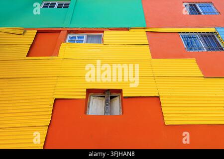 View of the vibrant colorful corrugated metal walls of the Caminito in La Boca, featuring bright yellow, orange, and green panels in Buenos Aires, Ciu Stock Photo