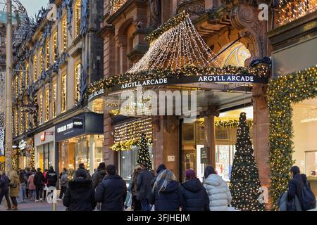 GLASGOW, SCOTLAND - DECEMBER 27, 2025: Shoppers walk past the Christmas-decorated entrance of Argyll Arcade on Buchanan Street, Glasgow, with fairy li Stock Photo
