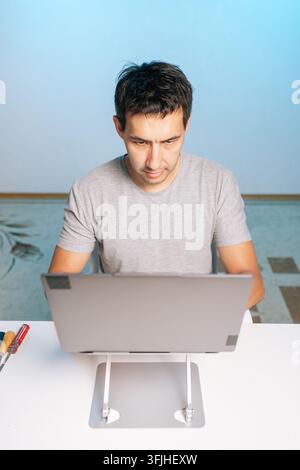 Concentrated technician, remote worker performing computer maintenance, diagnostics. Minimalist home office with screwdrivers on desk. Concept of IT Stock Photo