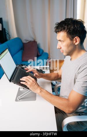Concentrated professional coding, studying remotely from comfortable living room. Side profile showing intense concept of screen. Ergonomic setup with Stock Photo