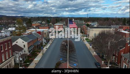 Powerful cinematic slow motion shot of American flag waving in breeze in small town America under dramatic daytime sky and clouds. Aerial, Manheim, Pe Stock Photo
