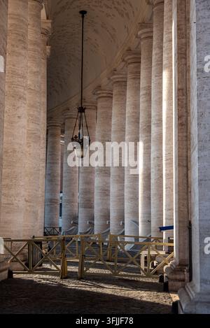 An architectural composition looking down the long covered corridor of berninis massive stone columns located in vatican city, rome, italy Stock Photo