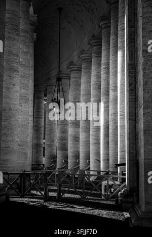 An architectural composition looking down the long covered corridor of berninis massive stone columns located in vatican city, rome, italy Stock Photo