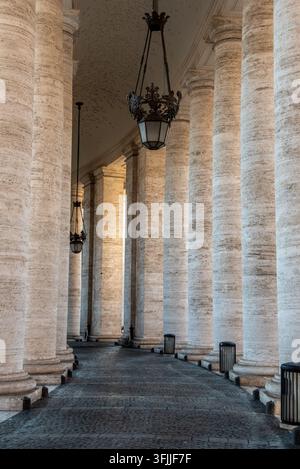 An architectural composition looking down the long covered corridor of berninis massive stone columns located in vatican city, rome, italy Stock Photo