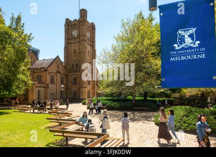 University of Melbourne Unimelb Parkville Campus, Old Arts Building 149 and Old Arts Tower with students and visitors. Flag with name logo. Stock Photo