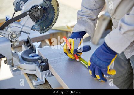 Man using a Sliding Miter Saw to cut Wood Stock Photo
