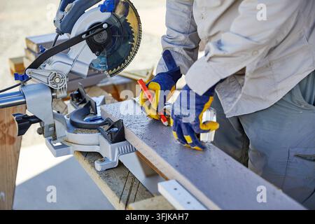 Man using a Sliding Miter Saw to cut Wood Stock Photo