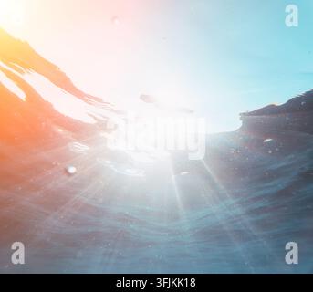 Underwater sunbeams pierce through clear tropical ocean waves illuminating tiny particles floating in deep water Stock Photo