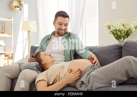 Happy loving couple relaxing on couch, pregnant woman and her husband sharing tender moment of joy. Stock Photo