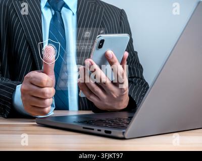 Business professional using smartphone and laptop with fingerprint shield scan interface. Biometric identity verification, secure mobile banking, auth Stock Photo