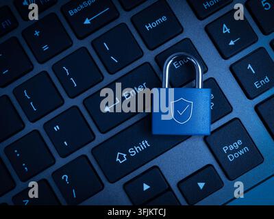 Blue padlock with shield symbol rests on computer keyboard background. Secure digital access, data protection, authentication, privacy, account safety Stock Photo
